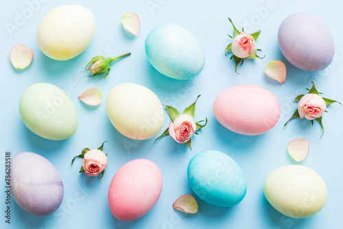 Happy Easter. Easter eggs on colored table with yellow roses. Natural dyed colorful eggs background top view with copy space