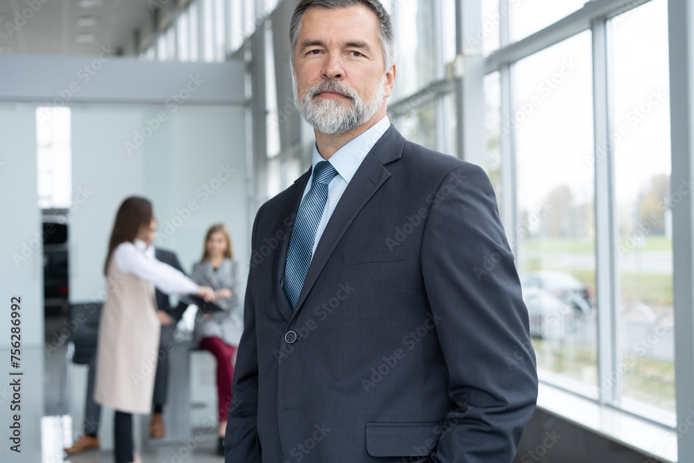 Happy middle aged business man ceo standing in office. Smiling mature confident professional executive manager, confident businessman leader wearing blue suit posing for corporate portrait Happy middle aged business man ceo standing in office. Smiling mature confident professional executive manager, confident businessman leader wearing blue suit posing for corporate portrait