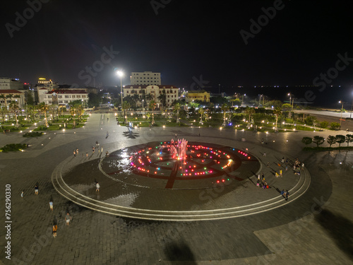 People enjoying the beautiful color display of the singing fountain at night in a public park in Tuy Hoa, Vietnam