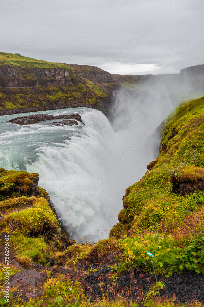 Cover page with copy space, Gullfoss waterfall with dramatic sky and green hills. Beautiful Icelandic landscape, huge cliff, water cascade and rock in moss Cover page with copy space, Gullfoss waterfall with dramatic sky and green hills. Beautiful Icelandic landscape, huge cliff, water cascade and rock in moss