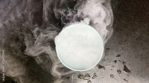 Image effect of smoke produced by putting water in dry ice in plastic bowl on black granit floor.