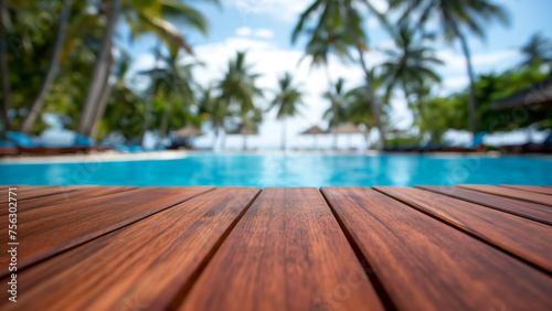 Leeres Holzdeck vor verschwommenem tropischem Swimmingpool im Urlaub, Hotel, Resort und Palmenhintergrund mit Platz für Produktpräsentation