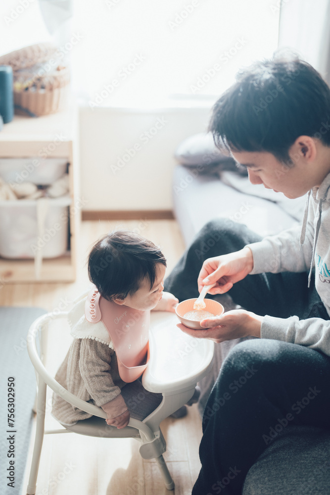 Obraz premium 赤ちゃんに離乳食を食べさせるお父さん