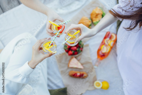 lanket with pillows and food on a wooden bridge. Bottle of strawberry and lemon smoothie photo