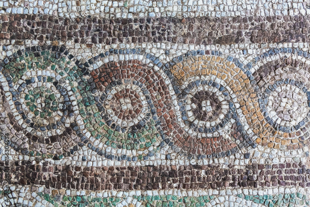 Ancient mosaic flooring shows intricate circular patterns with varied hues of weathered tiles. Izmir, Turkiye (Turkey)