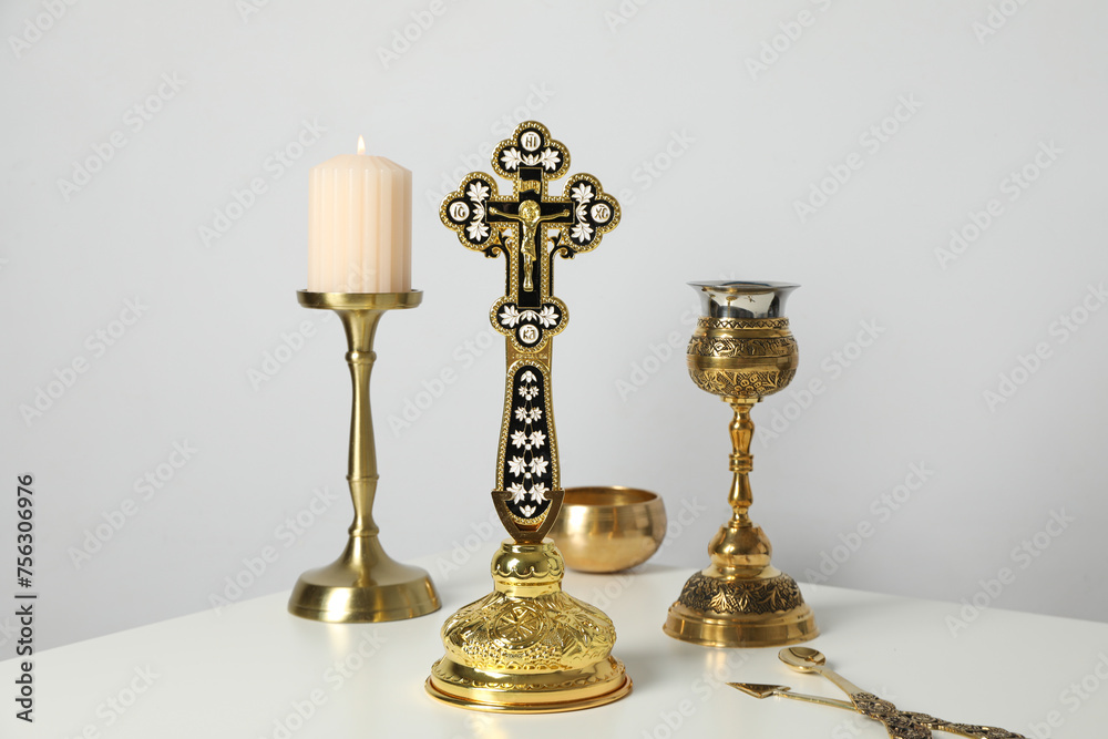 Candle, golden cup and cross on table on white background Candle, golden cup and cross on table on white background
