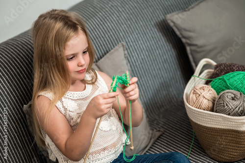 Little girl to knit while sitting on couch enjoying her hobby