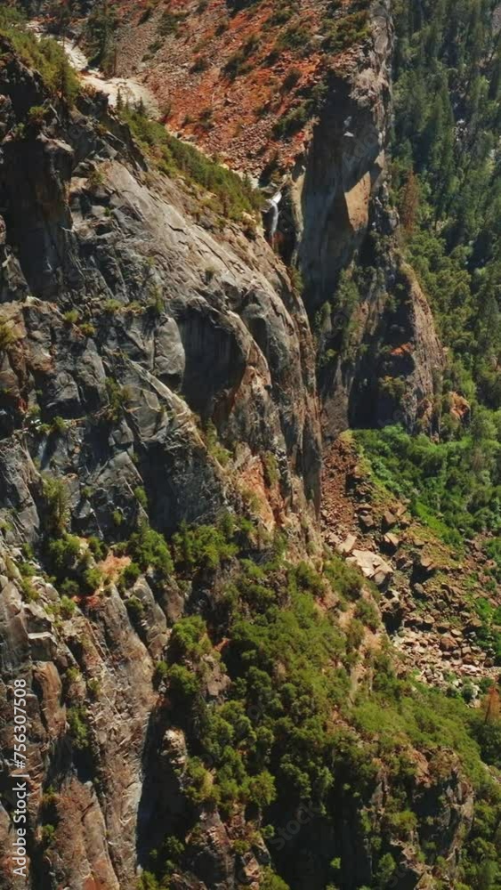 Splendid view of dangerous huge rock cliffs on sunny day. Beautiful pine tree forest growing at the foot. Aerial perspective. Vertical video. Splendid view of dangerous huge rock cliffs on sunny day. Beautiful pine tree forest growing at the foot. Aerial perspective. Vertical video.