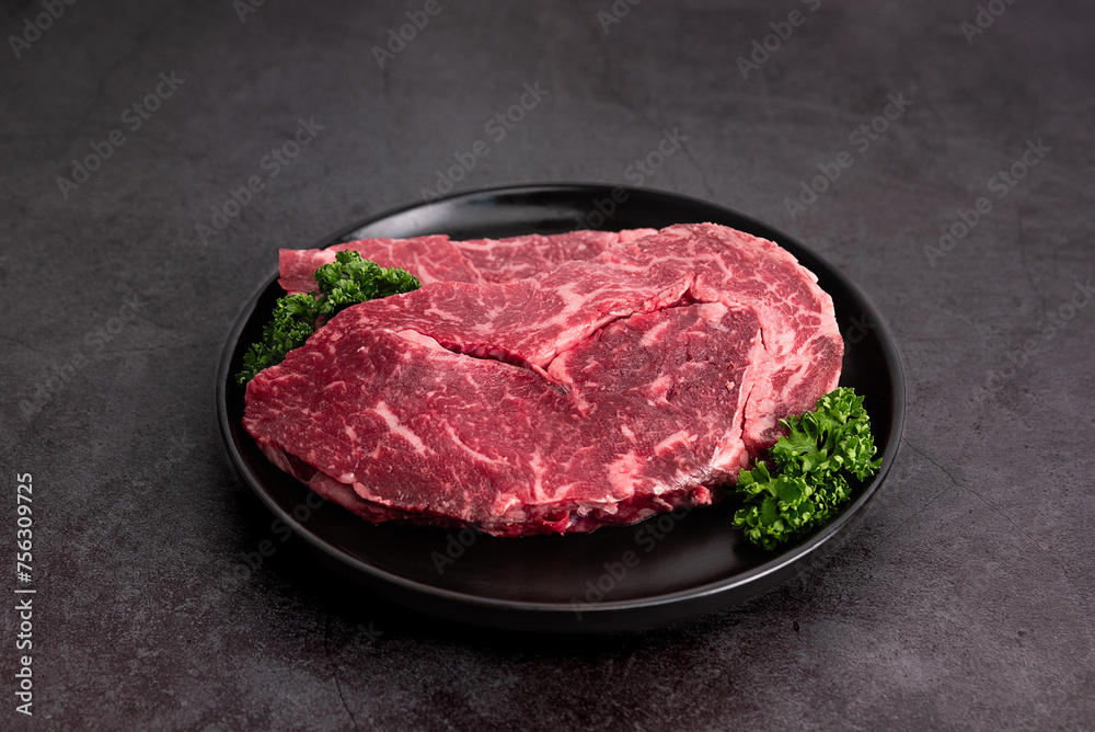 Plated beef on a dish against a black background