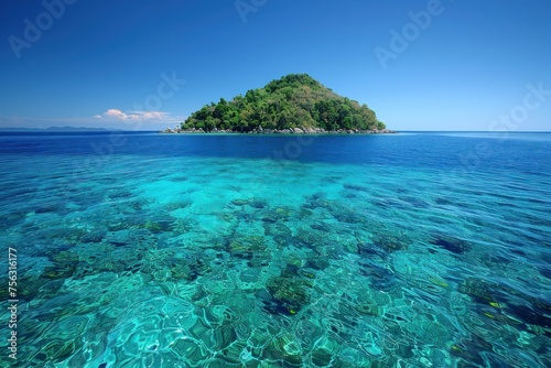 Lush greenery lines a rocky shore, where pristine turquoise waters meet a dramatic mountain backdrop under a clear sky.