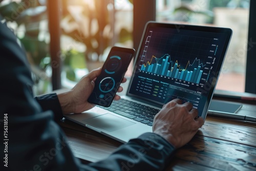 Businessman analyzing investment charts with laptop and mobile phone. Investment and trading concept