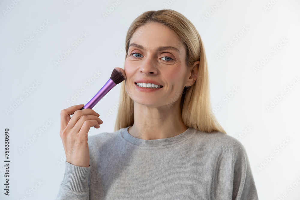 Pretty young blonde woman doing make up and smiling Pretty young blonde woman doing make up and smiling