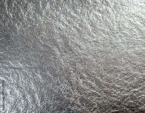 A silver surface with a hammered finish, showcasing the reflective quality of silver and the unique indentations from the hammering process. photo