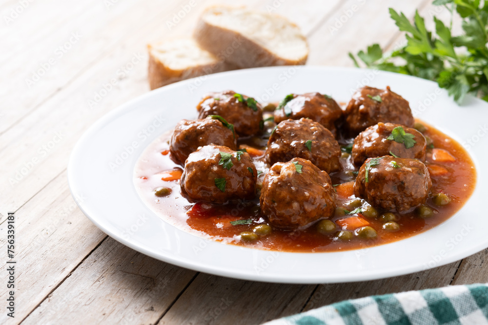 Meatballs, green peas and carrot with tomato sauce on wooden table