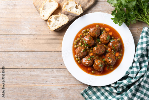 Meatballs, green peas and carrot with tomato sauce on wooden table. Top view. Copy space
