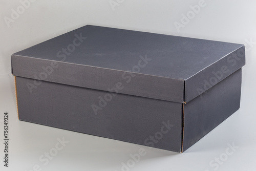 Closed gray cardboard shoebox on gray background, side view