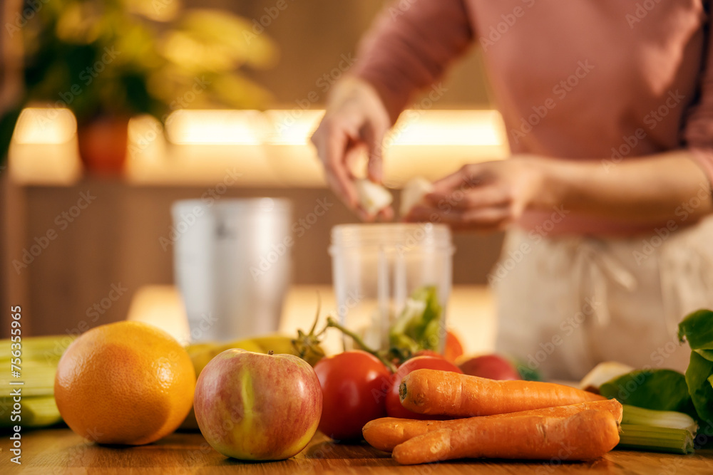 Close up of organic food on a table with woman preparing smoothie.