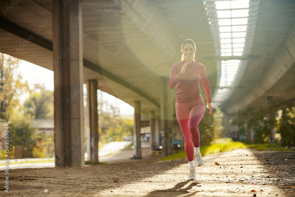A female jogger is jogging in urban exterior during her cardio training.