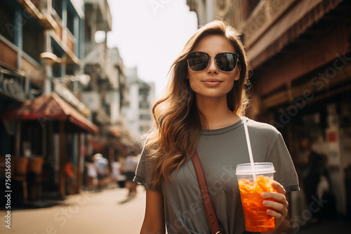 A girl drinking a soft drink from a glass while walking sightseeing in the cityA girl drinking a soft drink from a glass with a recycled straw while walking sightseeing in the city