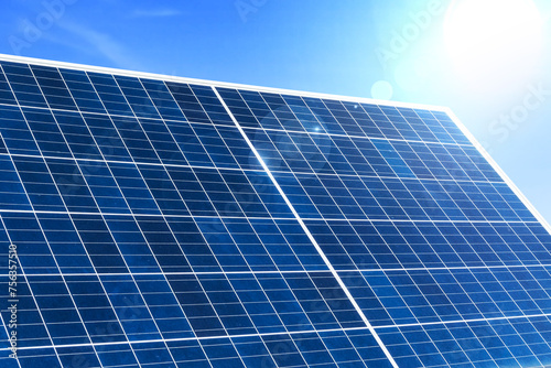 Image of solar panel with sunlight on blue sky background.