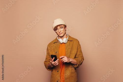 Happy young man using smartphone on vibrant peach background