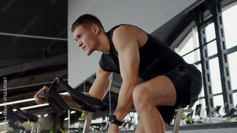 Pindiling Exercise A man is pedaling on an exercise bike at the gym, working out his thigh ...