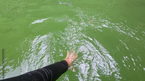 man's hand touching the water of a river or lake from a boat on a ride on the water on vacation photo
