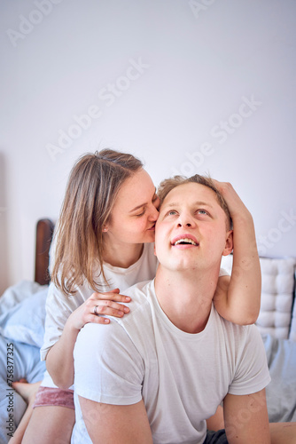 a young couple on the bed  the woman plays and bites the boy s ear