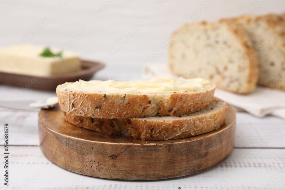 Slices of tasty bread with butter on white wooden table, closeup