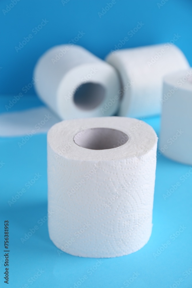 Soft toilet paper rolls on light blue background, closeup Soft toilet paper rolls on light blue background, closeup