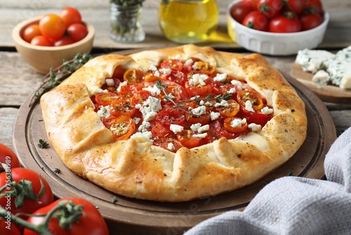 Tasty galette with tomato, thyme and cheese (Caprese galette) on wooden table, closeup