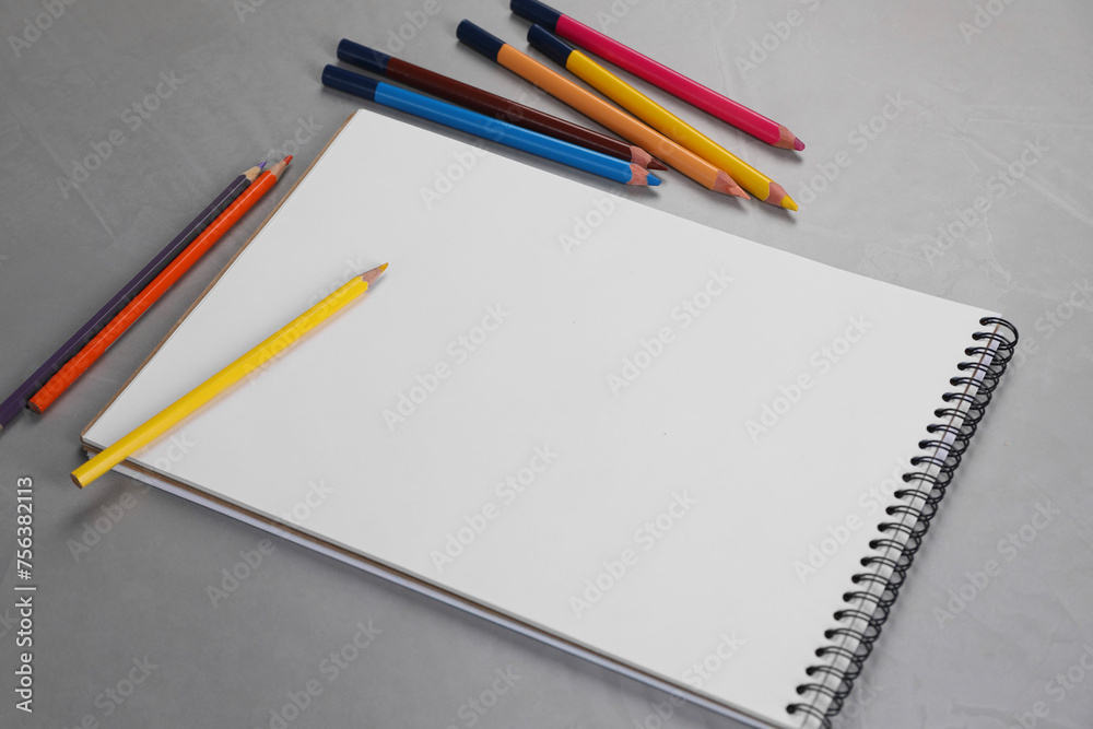 Empty sketchbook and colorful pencils on grey textured table, above view Empty sketchbook and colorful pencils on grey textured table, above view