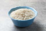 Raw basmati rice in bowl on grey table, closeup