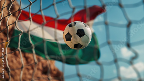 Soccer ball in the net with the flag of Hungary in the background