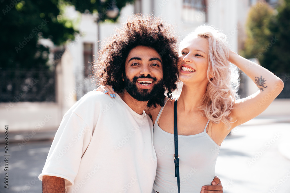 Fototapeta premium Smiling beautiful woman and her handsome boyfriend. Woman in casual summer jeans clothes. Happy cheerful family. Female having fun. Sexy couple posing in the street at sunny day. Embracing each other