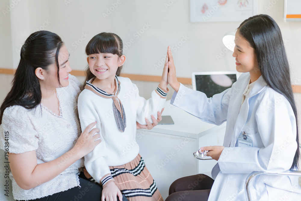 Fototapeta premium The doctor gave the little girl strength by touching her hand while her mother looked after her and gave her encouragement.