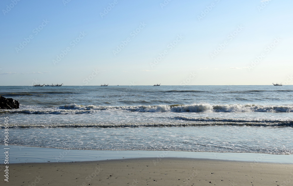 Deserted sandy beach in the morning on the Adriatic Sea with fishing boats under cloudless sky