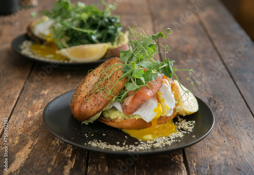 Tasty sandwich with avocado, salad and poached egg on a plate, close up, selective focus. Brunch on a rustic table.