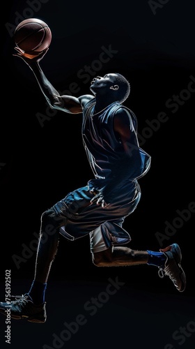 A dynamic action shot of a young professional basketball player isolated on a black background, capturing the energy and motion of the sport from a low angle. © vadymstock