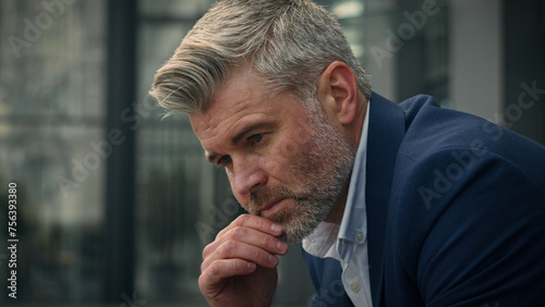Pensive sad worried sorrowful thoughtful middle-aged man senior mature business employer businessman think ponder problem solution grief put on glasses dreaming contemplate thinking in city outdoors
