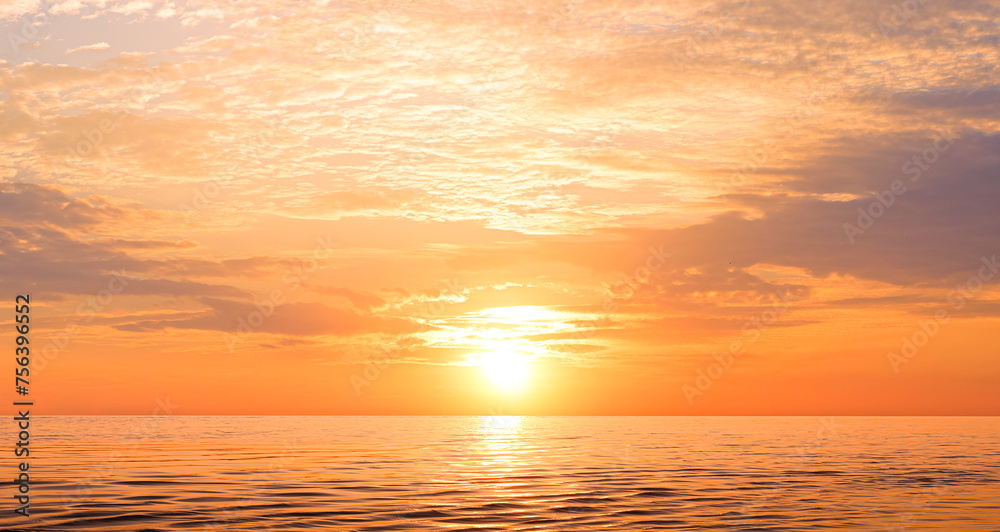 Sunset sky background over sea in the evening with beautiful yellow sunlight reflection on water surface in golden hour time
