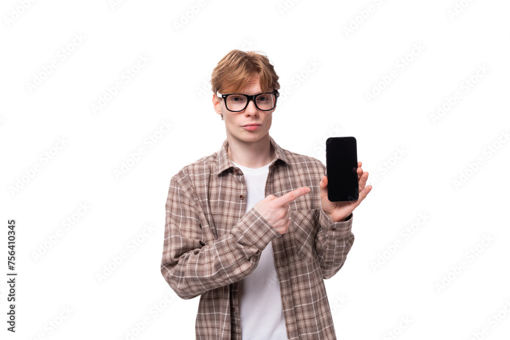 young man with red golden hair in glasses and a shirt holding a smartphone with a screen on an isolated background