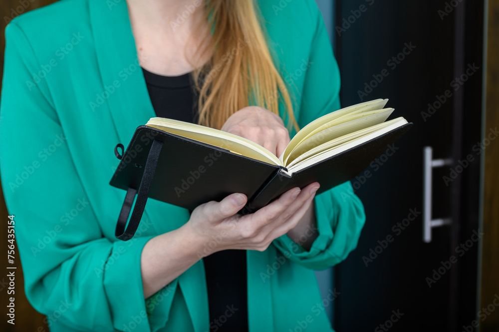 Młoda dziewczyna uczy się z książki, powtarza materiał przed egzaminem - obrazy, fototapety, plakaty 
