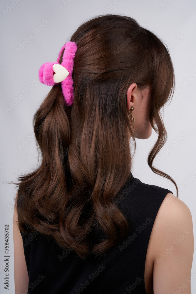 Close-up shot of a young woman with dark hair and a pink fluffy hair clip. Portrait of a young woman with a pink heart hair clip in her hair on a gray background. Back view.
Close-up shot of a young woman with dark hair and a pink fluffy hair clip. Portrait of a young woman with a pink heart hair clip in her hair on a gray background. Back view.