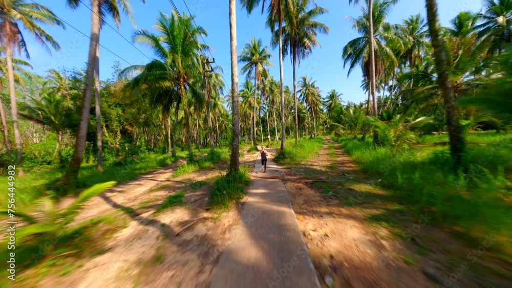 Caucasian woman runs along a scenic road with palm trees on tropical island in Thailand. Caucasian woman runs along a scenic road with palm trees on tropical island in Thailand.