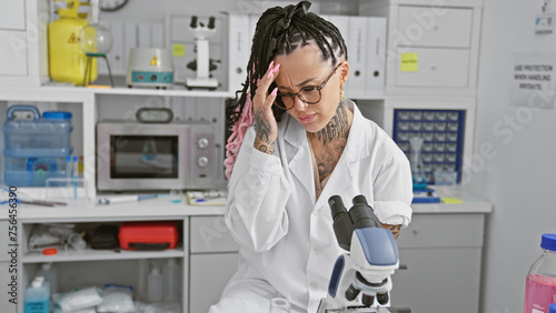 Stressed young hispanic woman scientist struggles with microscope science experiment in busy lab  an emblem of beauty in the male-dominated scientific research field.