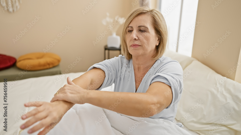 Mature caucasian woman applying cream on her arm in a bedroom, portraying self-care and wellness at home. Mature caucasian woman applying cream on her arm in a bedroom, portraying self-care and wellness at home.
