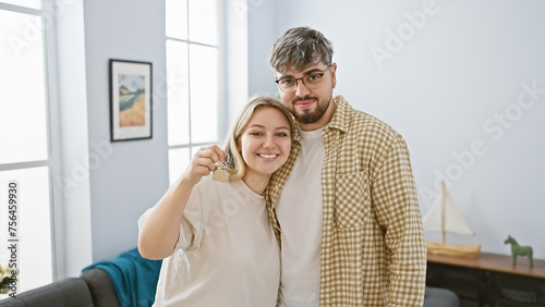 A happy couple holds house keys in a bright living room, symbolizing new homeownership and starting together.