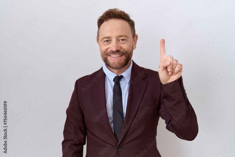 Middle age business man with beard wearing suit and tie showing and pointing up with finger number one while smiling confident and happy. Middle age business man with beard wearing suit and tie showing and pointing up with finger number one while smiling confident and happy.
