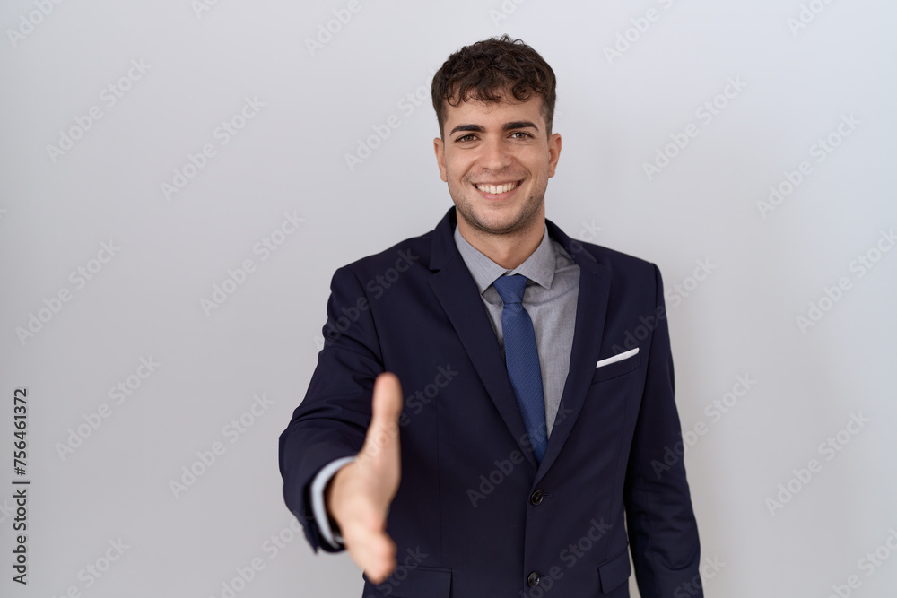 Young hispanic business man wearing suit and tie smiling friendly offering handshake as greeting and welcoming. successful business. Young hispanic business man wearing suit and tie smiling friendly offering handshake as greeting and welcoming. successful business.